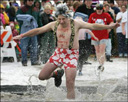 man in a wig and shorts jumping into icy lake